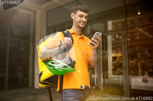 Image of Young man as a courier delivering package using gadgets