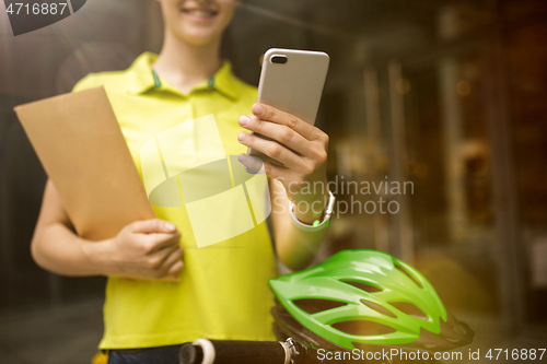 Image of Young woman as a courier delivering package using gadgets