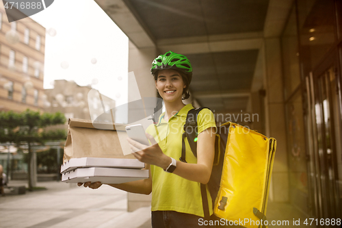 Image of Young woman as a courier delivering pizza using gadgets