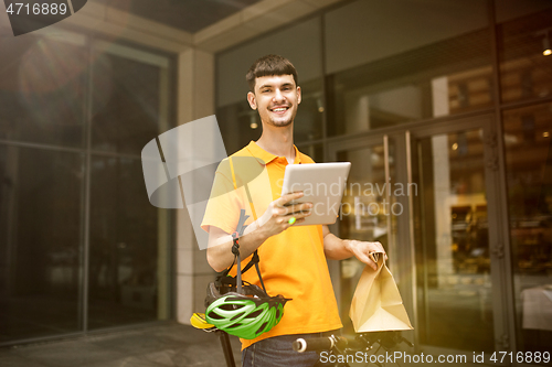 Image of Young man as a courier delivering package using gadgets