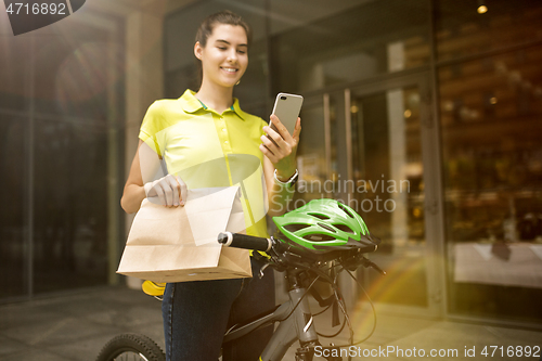 Image of Young woman as a courier delivering package using gadgets