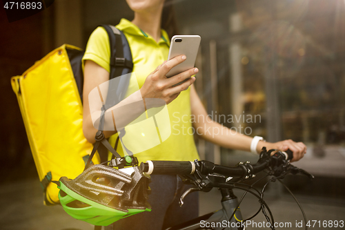 Image of Young woman as a courier delivering food using gadgets