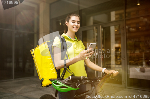 Image of Young woman as a courier delivering food using gadgets