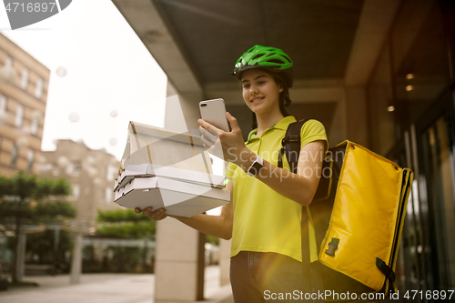 Image of Young woman as a courier delivering pizza using gadgets