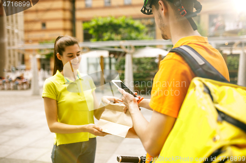 Image of Young man as a courier delivering package using gadgets