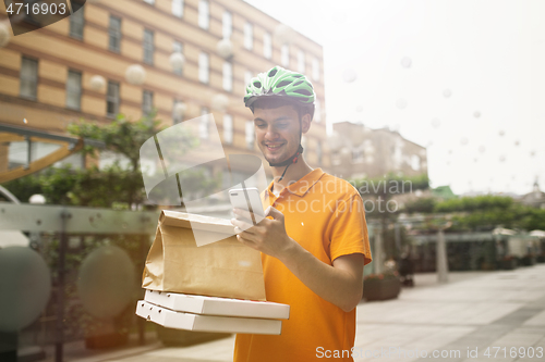 Image of Young man as a courier delivering pizza using gadgets