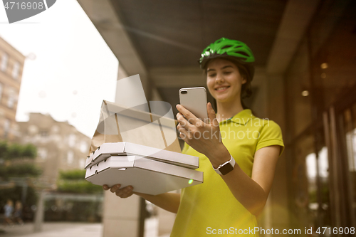 Image of Young woman as a courier delivering pizza using gadgets