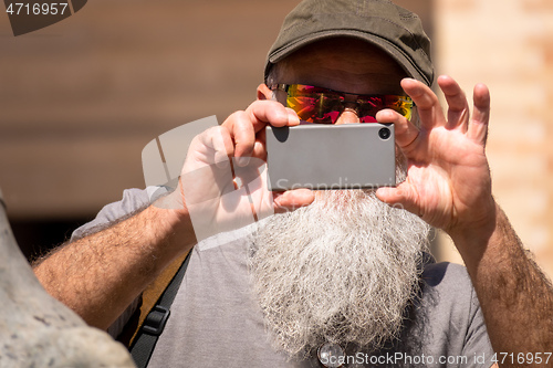 Image of man with a beard taking a photograph with his smart phone