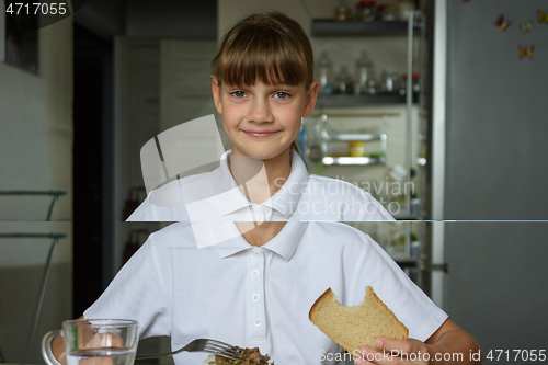 Image of Portrait of a happy girl having dinner at the table in the kitchen