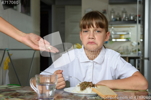 Image of The girl does not like the medicines offered by her mother before dinner