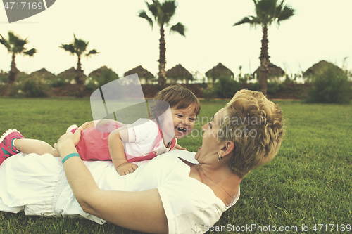 Image of mother and little daughter playing at backyard