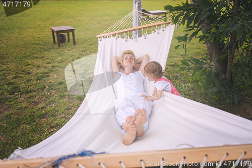 Image of mother and a little daughter relaxing in a hammock