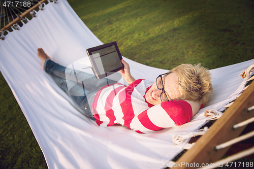 Image of woman using a tablet computer while relaxing on hammock