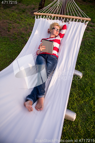 Image of woman using a tablet computer while relaxing on hammock