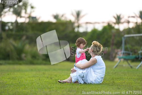 Image of mother and little daughter playing at backyard