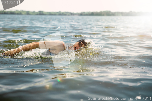 Image of Professional triathlete swimming in river\'s open water