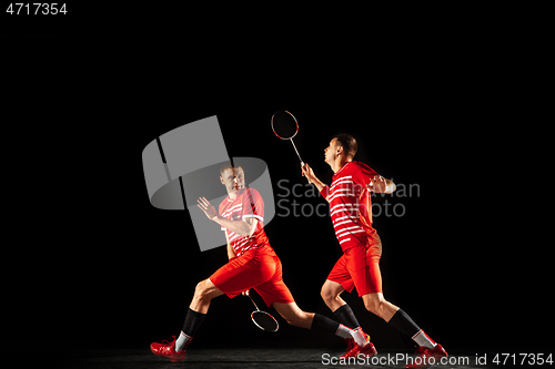 Image of Young man playing badminton isolated on black studio background