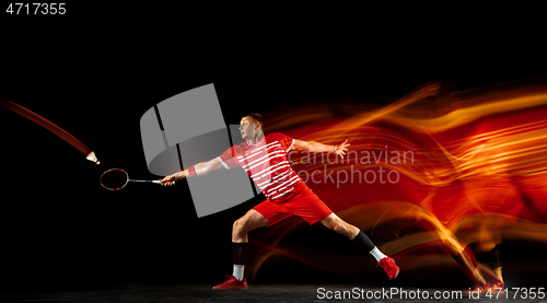 Image of Young man playing badminton isolated on black studio background