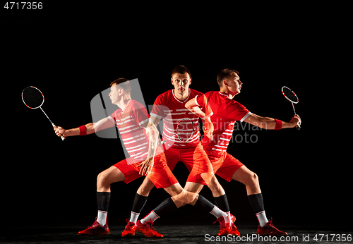 Image of Young man playing badminton isolated on black studio background