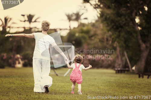 Image of mother and little daughter playing at backyard