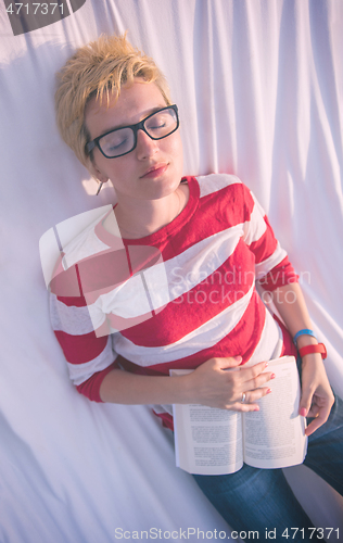 Image of woman reading a book while relaxing on hammock