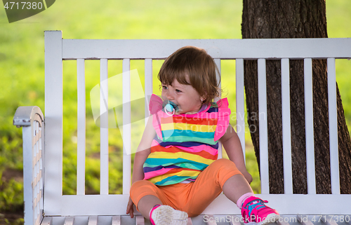 Image of cute little girl sitting on wooden bench