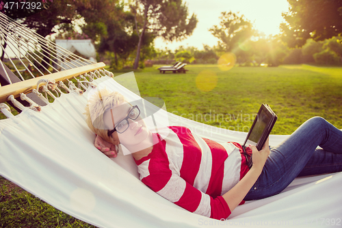 Image of woman using a tablet computer while relaxing on hammock