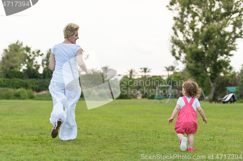 Image of mother and little daughter playing at backyard