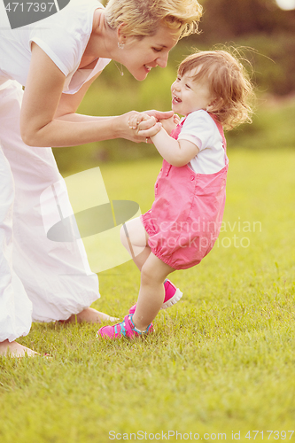 Image of mother and little daughter playing at backyard