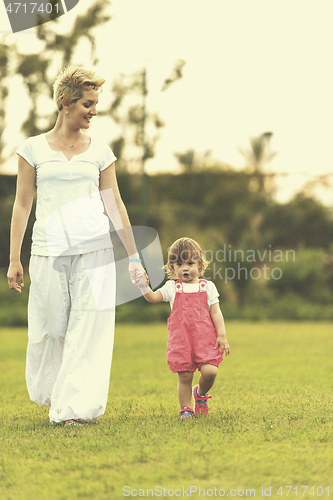 Image of mother and little daughter playing at backyard