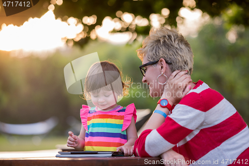 Image of mom and her little daughter using tablet computer