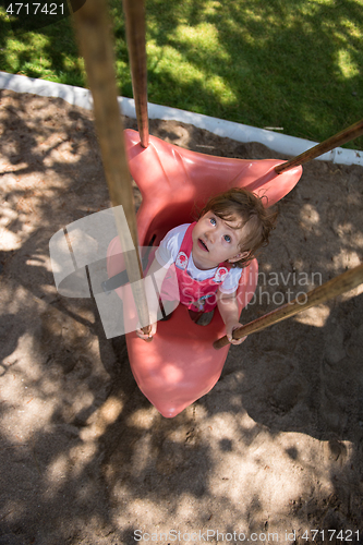 Image of little girl swinging  on a playground