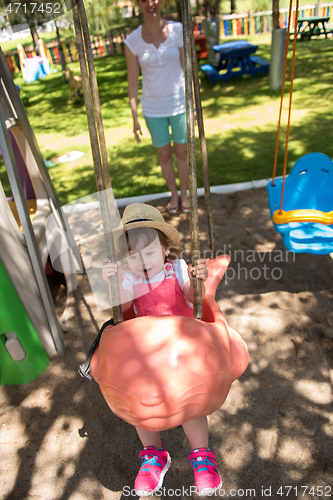 Image of mother and daughter swinging in the park