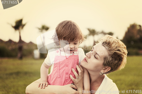 Image of mother and little daughter playing at backyard