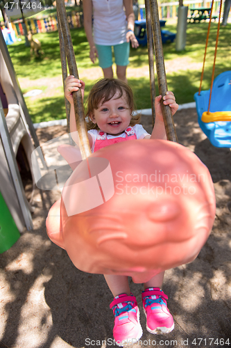 Image of mother and daughter swinging in the park