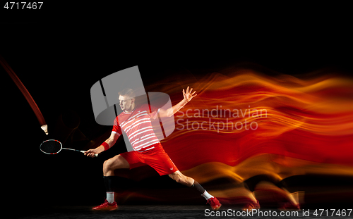 Image of Young man playing badminton isolated on black studio background