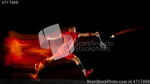 Image of Young man playing badminton isolated on black studio background