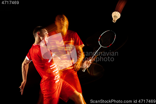 Image of Young man playing badminton isolated on black studio background