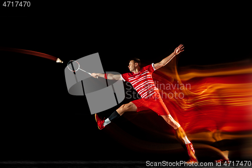 Image of Young man playing badminton isolated on black studio background