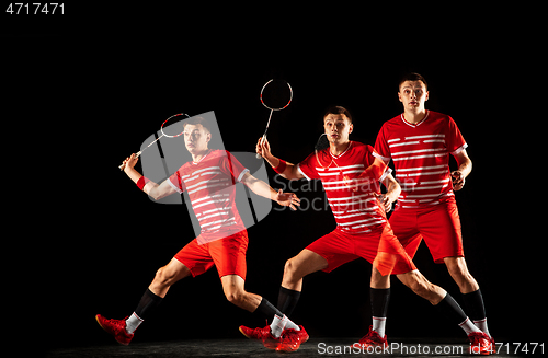 Image of Young man playing badminton isolated on black studio background