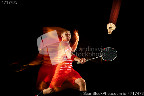 Image of Young man playing badminton isolated on black studio background