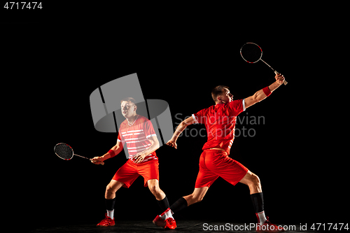 Image of Young man playing badminton isolated on black studio background