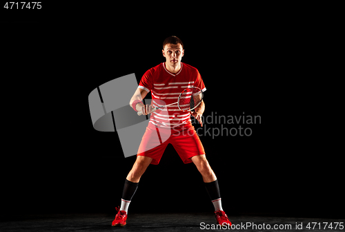 Image of Young man playing badminton isolated on black studio background