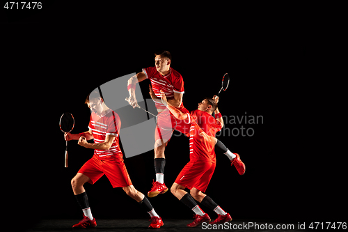 Image of Young man playing badminton isolated on black studio background