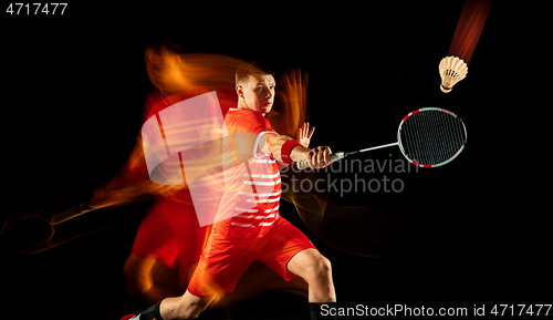 Image of Young man playing badminton isolated on black studio background