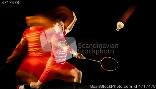 Image of Young man playing badminton isolated on black studio background