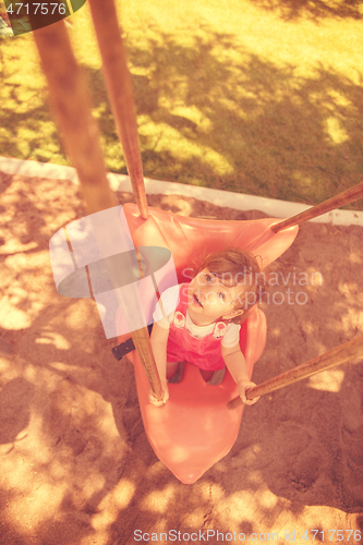 Image of little girl swinging  on a playground