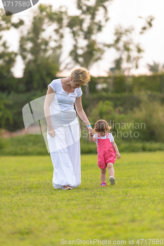 Image of mother and little daughter playing at backyard