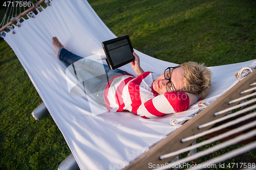 Image of woman using a tablet computer while relaxing on hammock