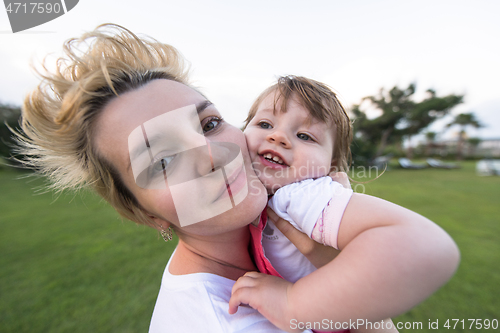 Image of mother and little daughter playing at backyard